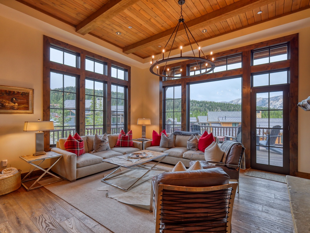 Sink into plush seating beneath soaring wood beams while you gaze at mountain views through floor-to-ceiling windows in your elegant alpine retreat.