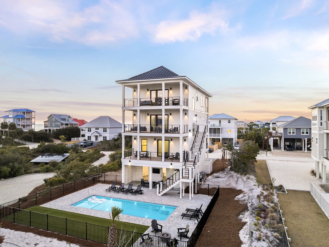 This impressive four-story coastal rental sits among charming beach houses, featuring a private pool and multiple balconies.