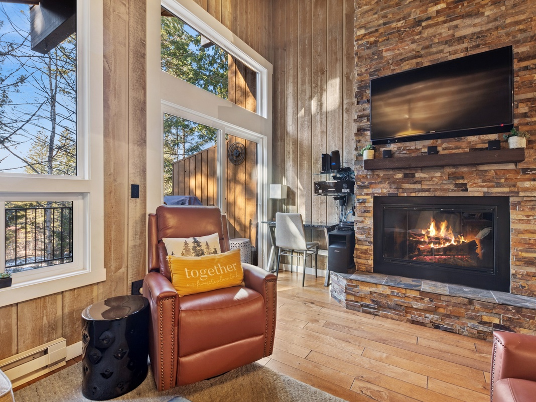 Curl up in your cozy leather chair by the crackling fireplace, watching flames dance while sunlight streams through tall windows.