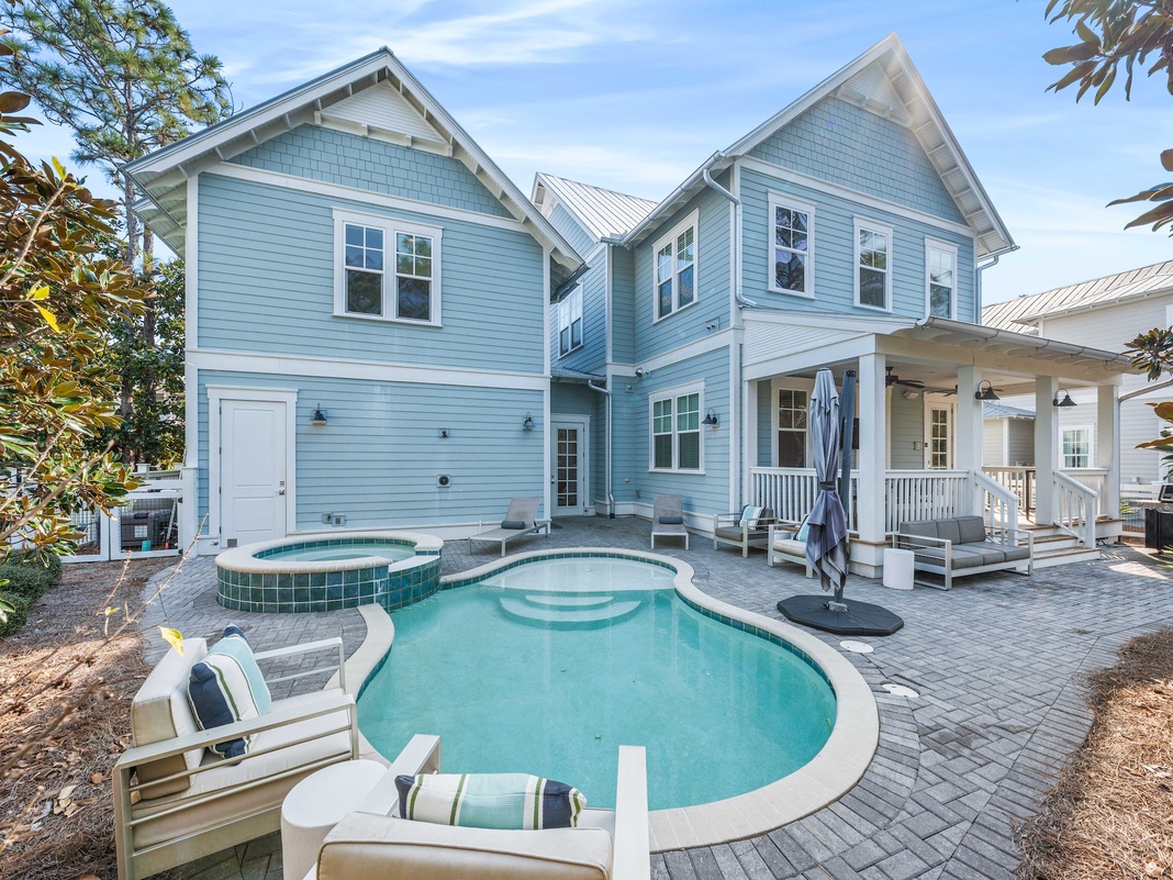 Beautiful coastal home featuring a private pool and hot tub surrounded by elegant outdoor seating and lush landscaping.