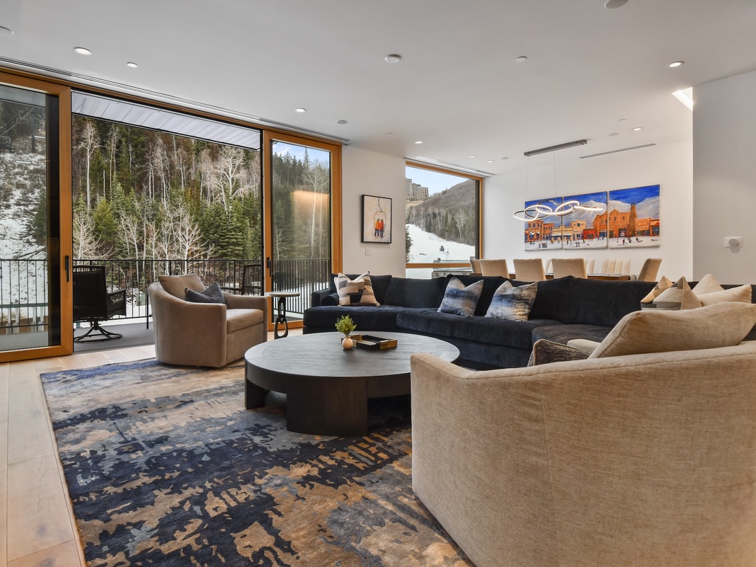 Sink into plush seating while gazing at snow-dusted mountains through floor-to-ceiling windows in your elegant living space.