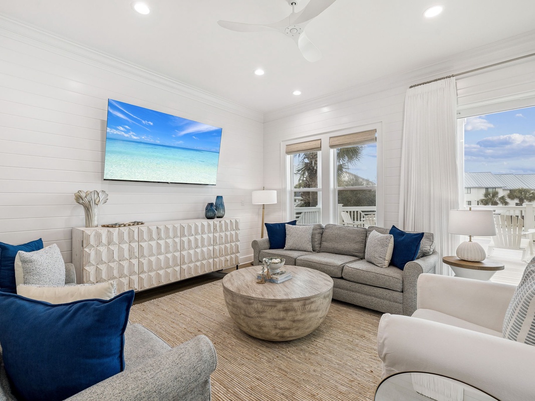 Unwind in your bright living space with coastal views through floor-to-ceiling windows and comfortable seating perfect for relaxing.