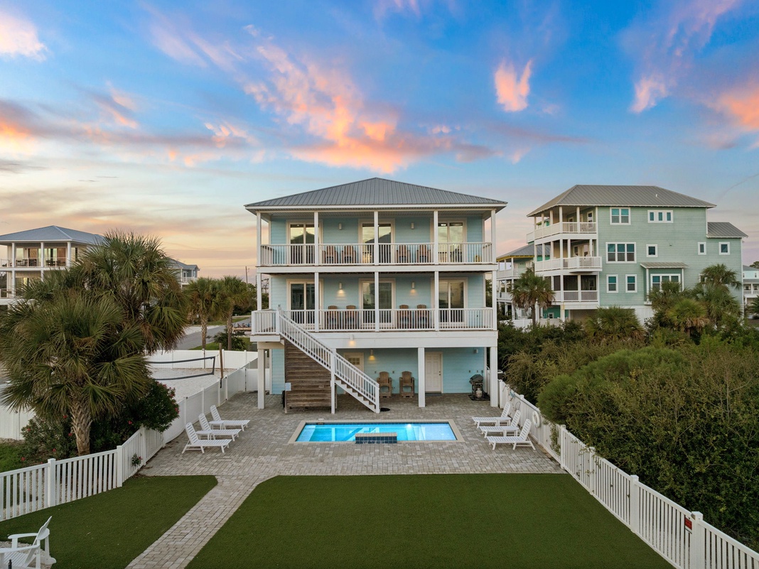 This coastal retreat features a private pool, spacious lawn, and multiple balconies set among palm trees and neighboring beach homes, creating a peaceful backdrop for your getaway.