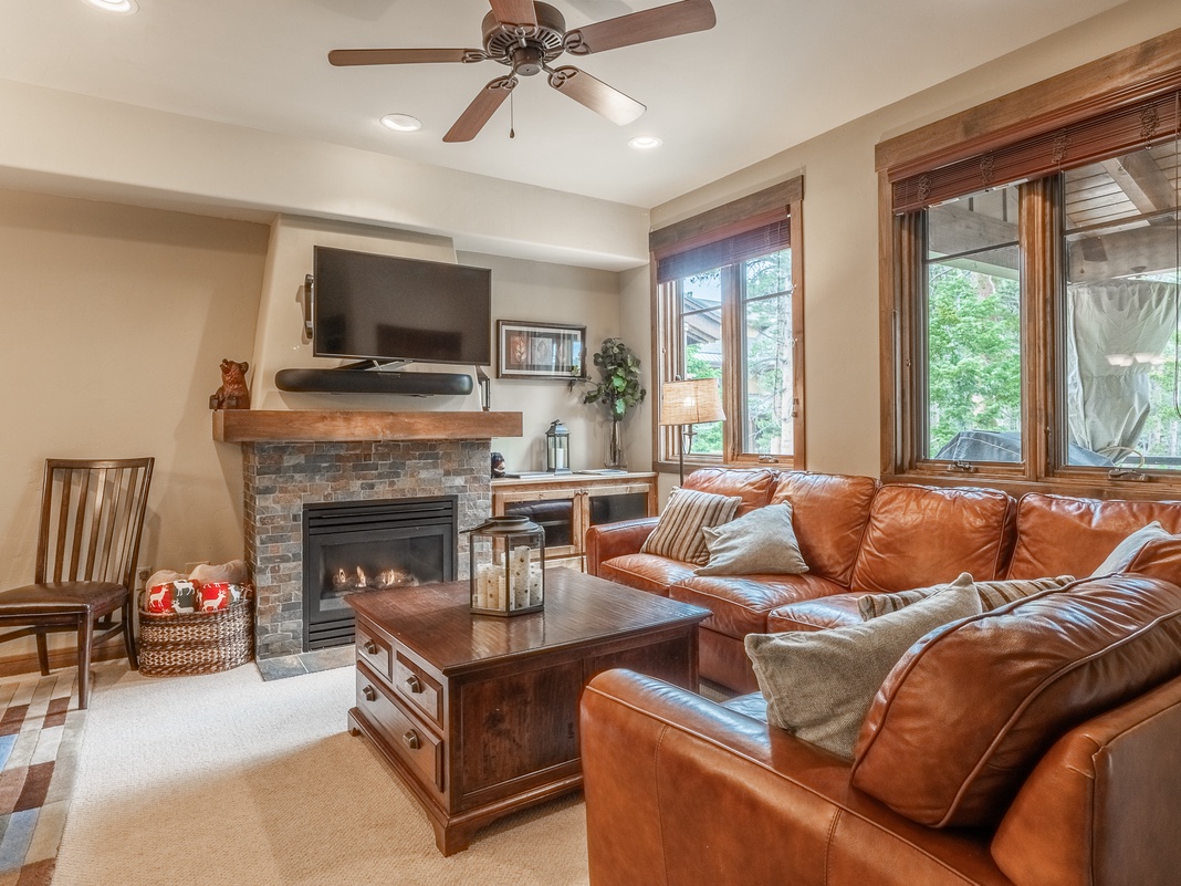 Sink into plush leather seating in your inviting living room, where a cozy fireplace and views of surrounding greenery create the perfect retreat after a day of mountain adventures.