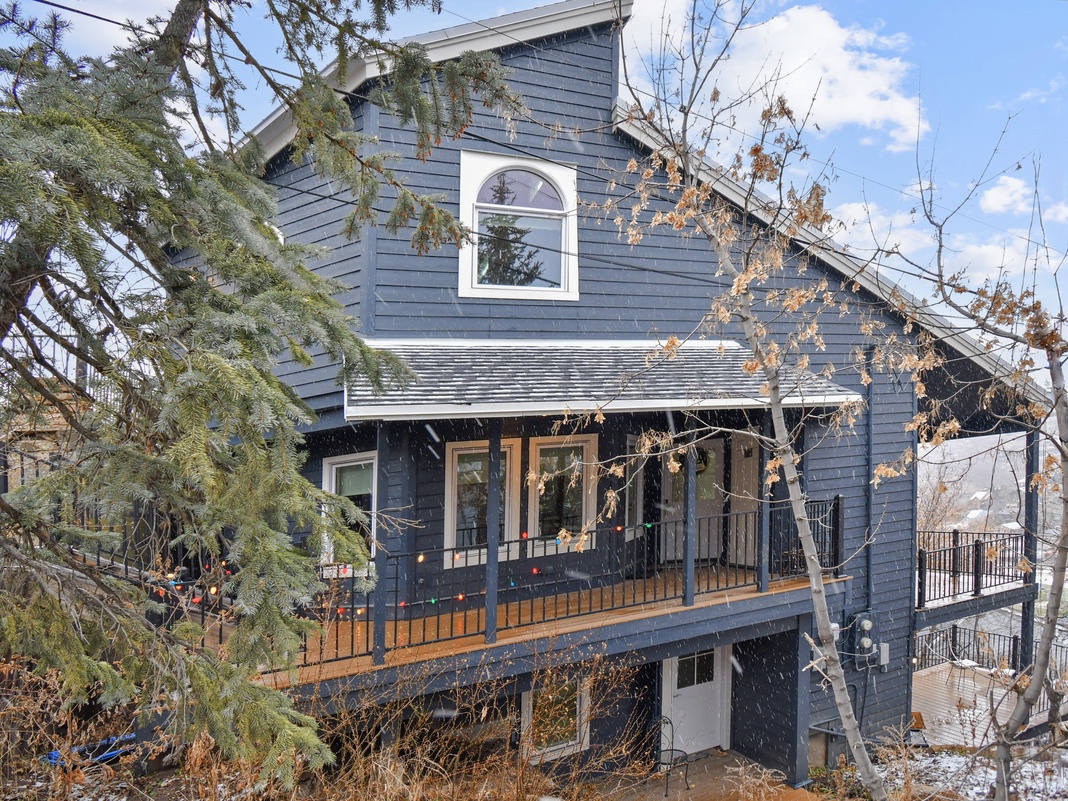 Charming blue cottage with welcoming front porch and mountain retreat atmosphere, surrounded by natural winter landscape.