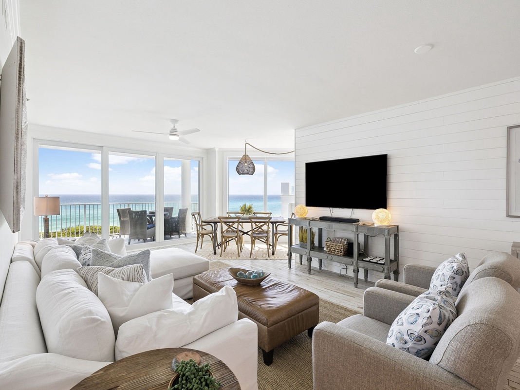Relax in your bright coastal living space where ocean views stretch endlessly beyond floor-to-ceiling windows.
