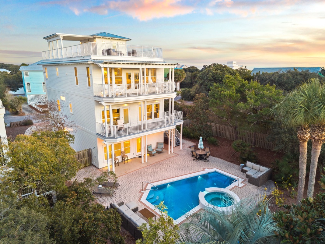 Stunning three-story coastal home featuring a private pool and hot tub surrounded by lush tropical landscaping and multiple balconies.