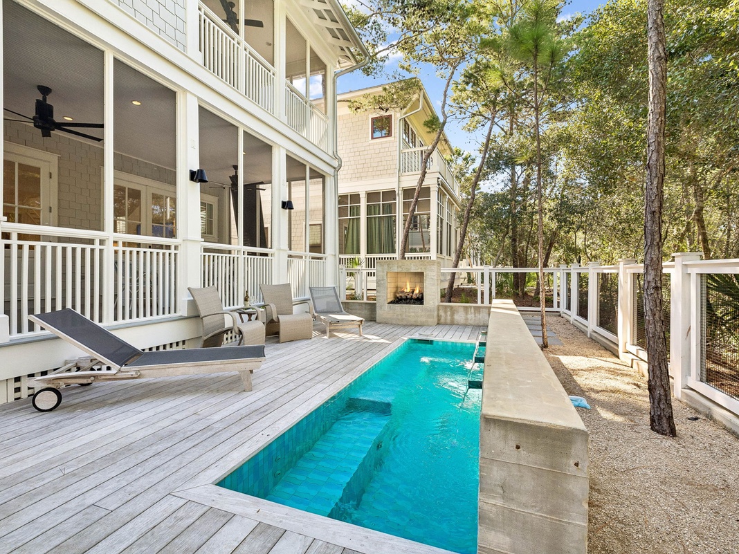 Sunny coastal elegance meets private escape—your own lap pool nestled among shade trees, lounge chairs at the ready, with screened porches and balconies framing the property.
