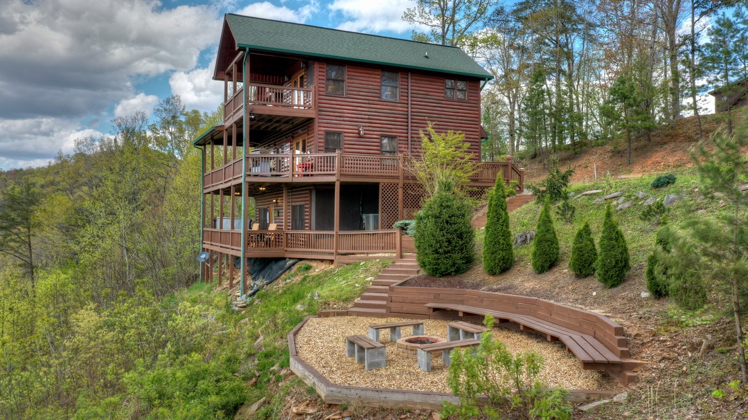 A spacious mountain cabin with multiple levels of decks, nestled into a wooded hillside with panoramic views and a private outdoor fire pit area perfect for evening gatherings.