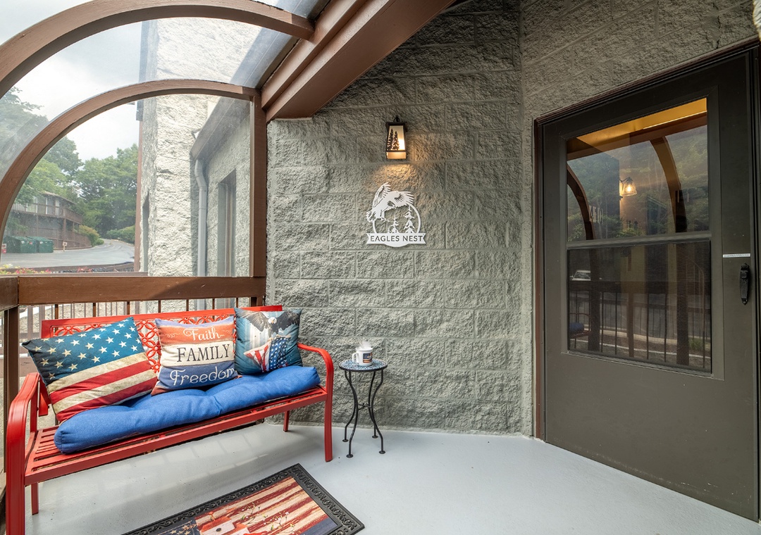 Eagle's Nest features a welcoming covered entryway with cozy seating, mountain views, and distinctive architectural details marking your arrival to this peaceful retreat.