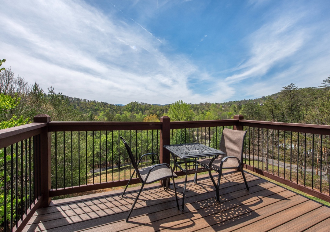 Step onto your private deck and breathe in mountain views that stretch for miles, where morning coffee feels magical at this peaceful table for two.