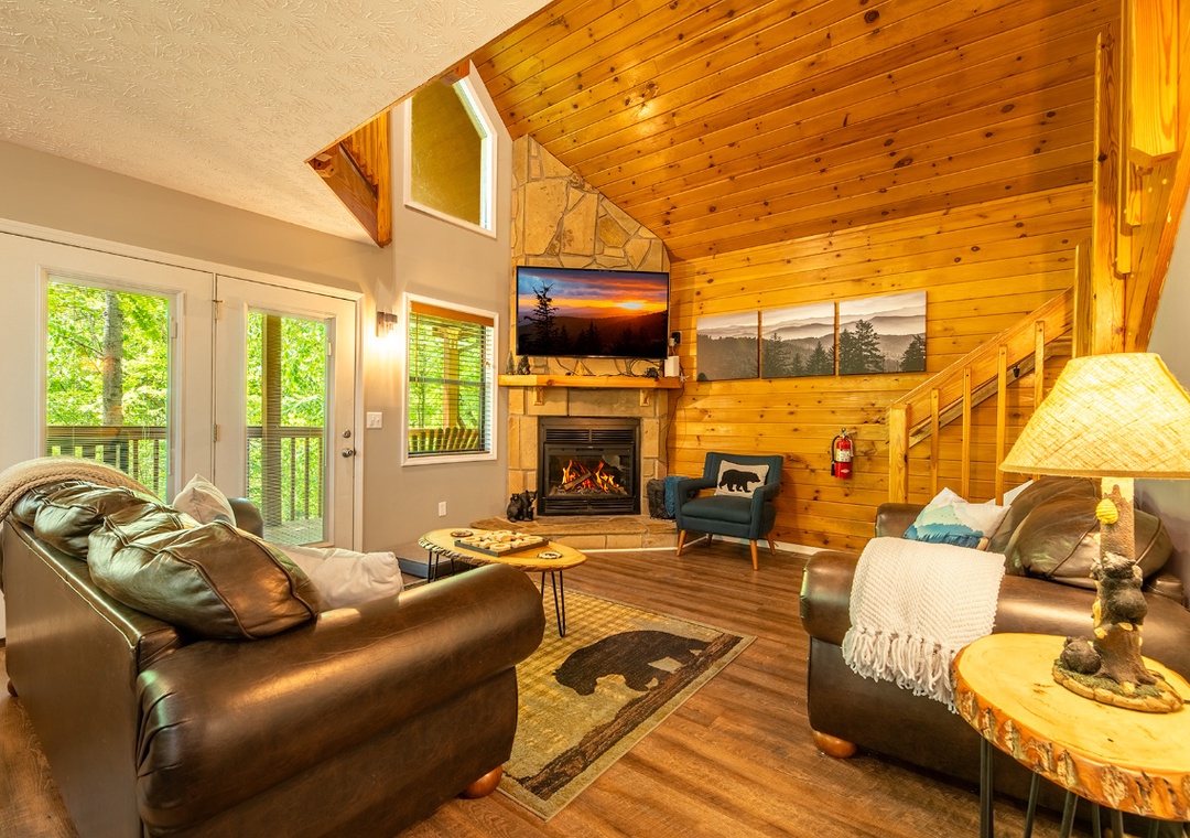 Sink into plush leather seating by the warm glow of your fireplace, surrounded by rustic wood beams and natural light streaming through expansive windows, inviting pure mountain relaxation.