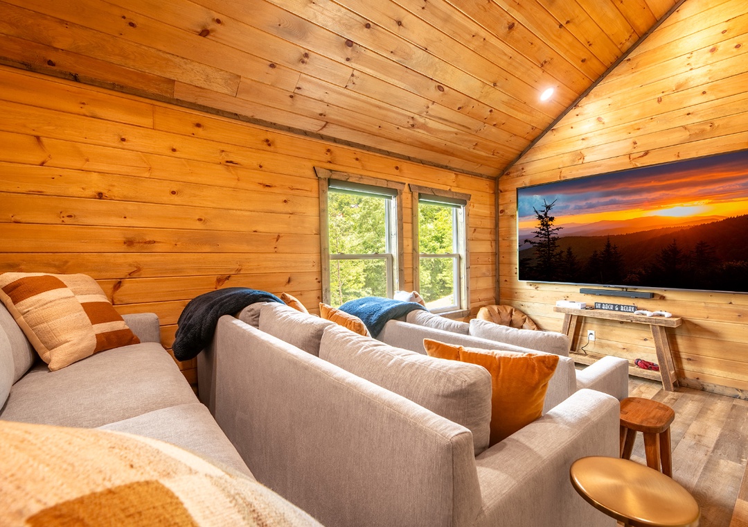 Sink into the plush sofa and enjoy movie nights under warm wood-beam ceilings, with natural light streaming through and your favorite show on the big screen.