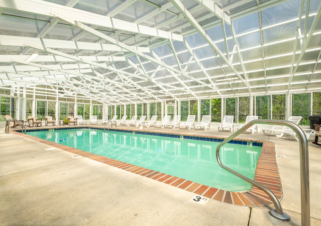 This enclosed pool offers year-round swimming with panoramic forest views and comfortable poolside lounging.