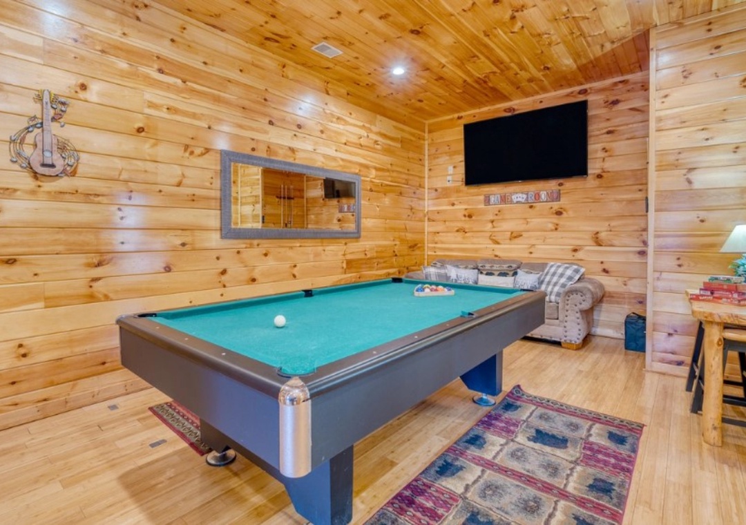 Your game room awaits with a professional pool table, cozy seating, and big screen TV for perfect cabin entertainment nights.