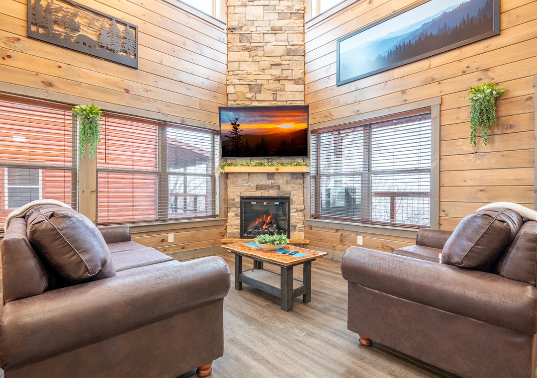 Sink into plush leather chairs by your cozy fireplace, surrounded by warm wood walls and nature-inspired artwork that creates the perfect mountain retreat atmosphere.