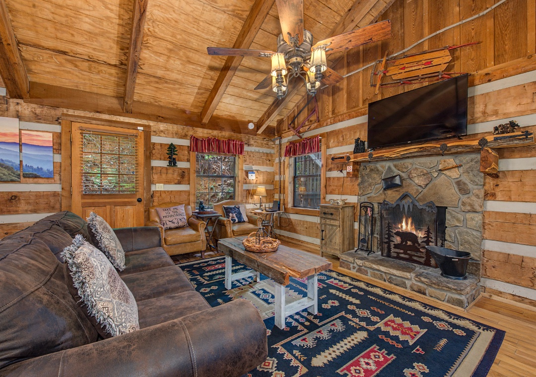Unwind in your cozy living room featuring cathedral ceilings, a crackling stone fireplace, and warm wood accents that create the perfect mountain retreat atmosphere.