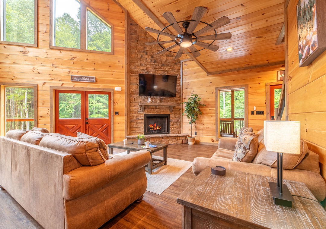 Gather around your glowing stone fireplace beneath cathedral ceilings, where plush seating and forest views through expansive windows make every moment feel like a true mountain escape.