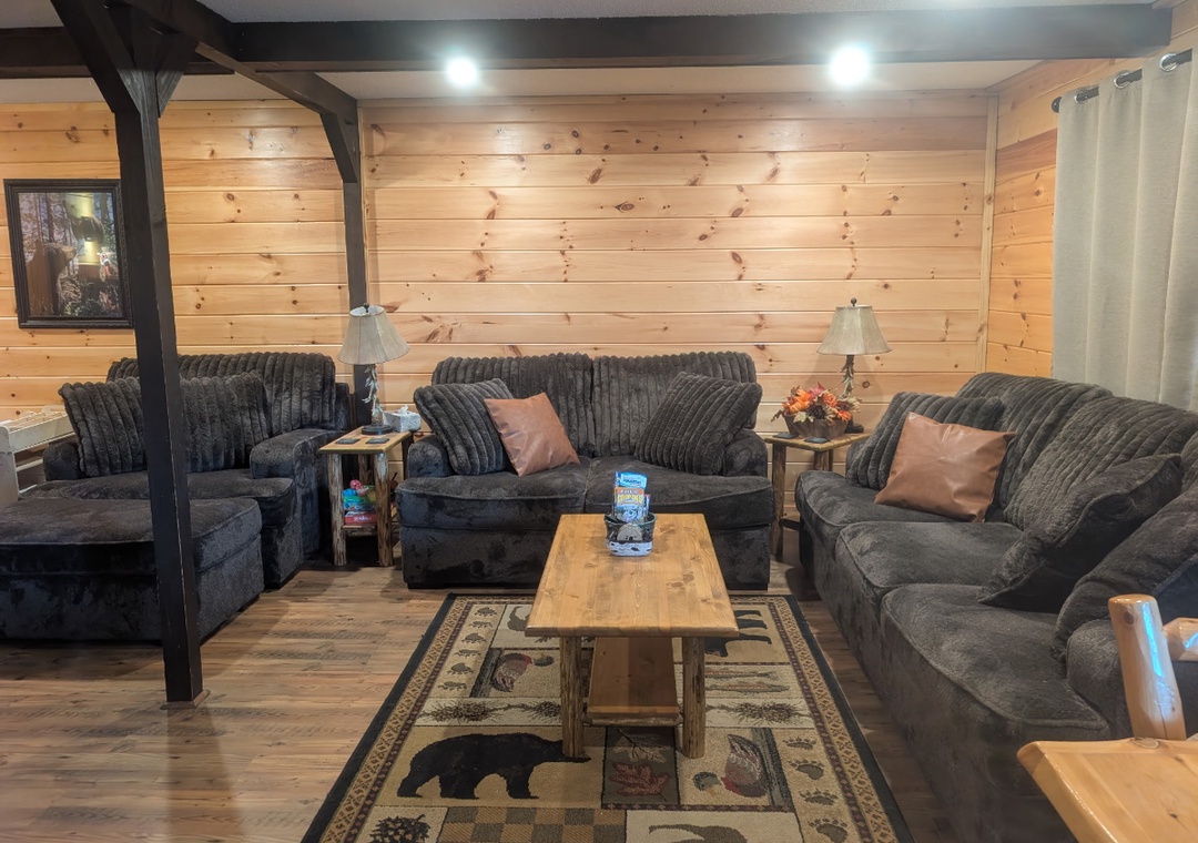 Sink into plush seating in your cozy living room, where rustic wood walls and comfortable furnishings create the perfect retreat for relaxation.
