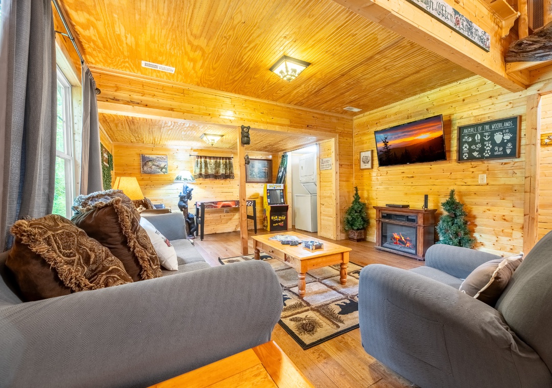 Relax in your cozy cabin living room, where warm knotty pine walls and a glowing fireplace create the perfect woodland retreat for family game nights or quiet evenings in.