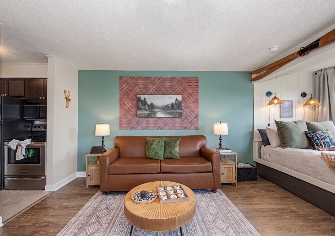 Settle into your cozy studio where a plush leather sofa and welcoming bed await. Natural wood accents and soothing teal walls create a peaceful retreat after a day exploring the mountains.