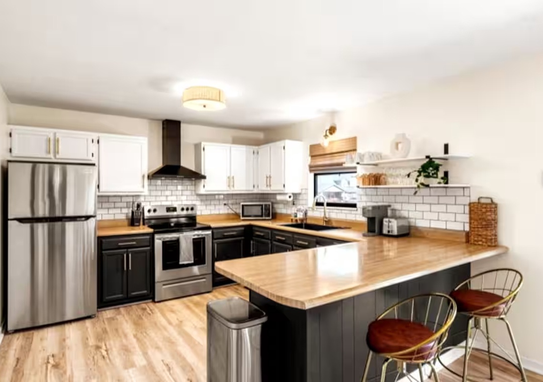 Your fully equipped kitchen awaits with warm countertops, stainless steel appliances, and a breakfast bar perfect for morning coffee.
