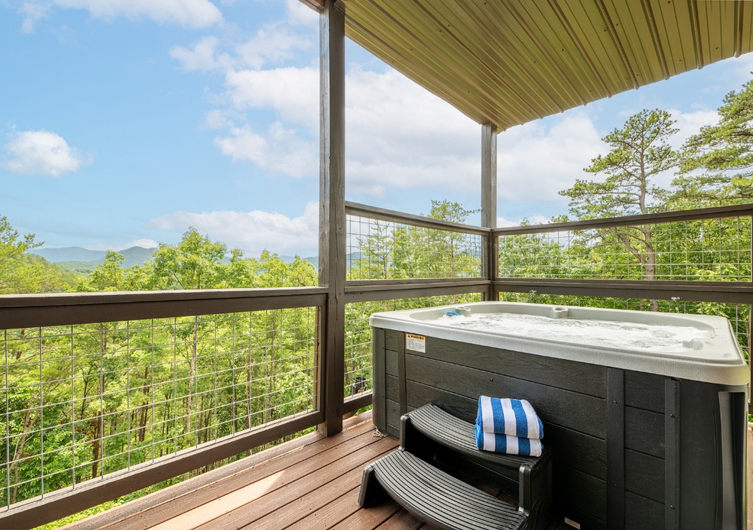 Soak beneath a covered terrace with sweeping mountain vistas stretching across lush forest. The deck offers a serene retreat where you can unwind in comfort surrounded by nature's beauty.