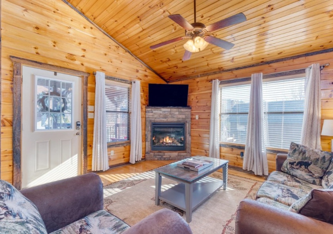 Cozy up in your rustic living room with crackling fireplace, warm wood walls, and comfortable seating for perfect mountain cabin relaxation.