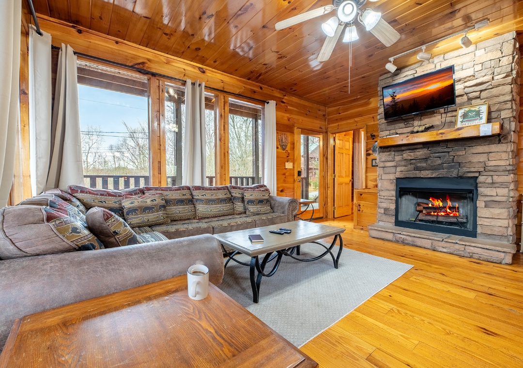 Cozy up by the crackling stone fireplace in your rustic living room, where warm wood tones and panoramic views create the perfect mountain getaway.