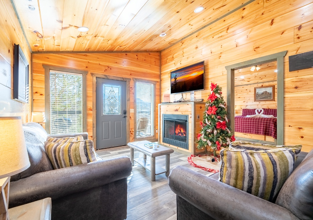 Unwind in your cozy cabin living room with crackling fireplace, comfortable seating, and warm wood walls creating the perfect mountain retreat.