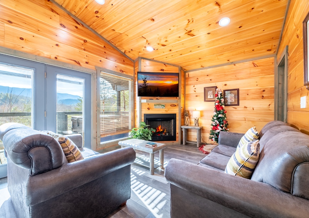 Warm up by your crackling fireplace while enjoying mountain views through expansive windows in this cozy cabin living room.