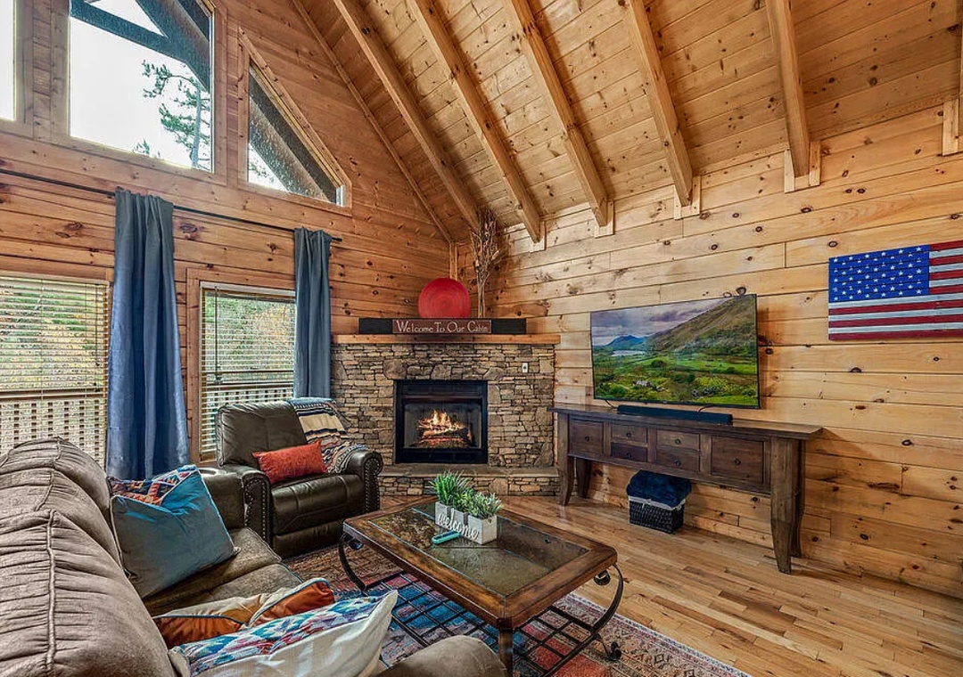 Unwind in your cozy cabin living room with crackling fireplace, plush seating, and rustic charm creating the perfect mountain getaway atmosphere.