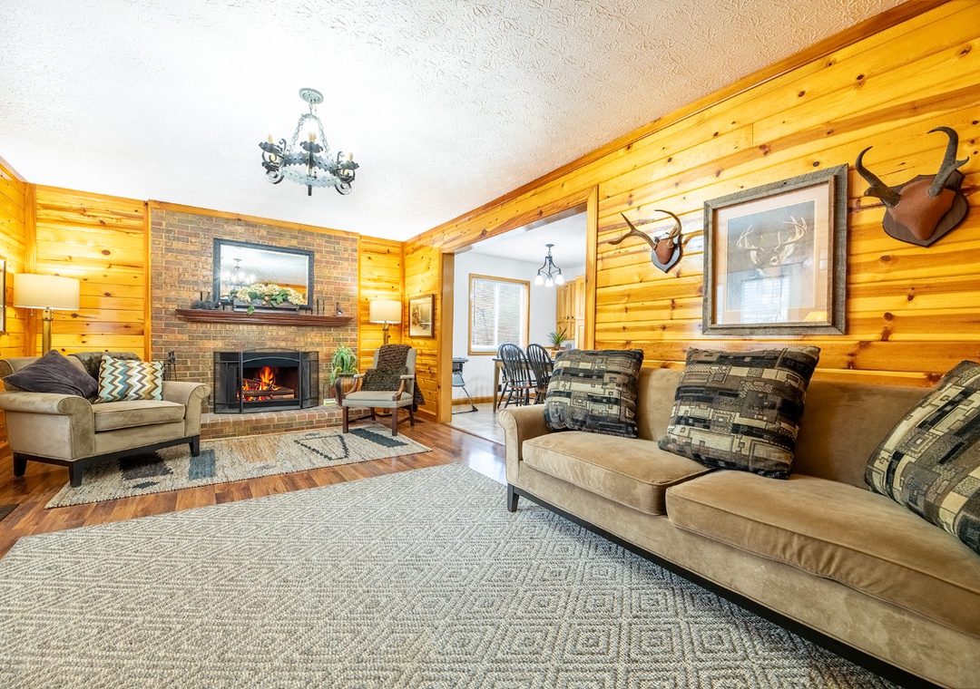Cozy up in your rustic cabin living room, where warm wood walls and a crackling fireplace create the perfect mountain retreat atmosphere.