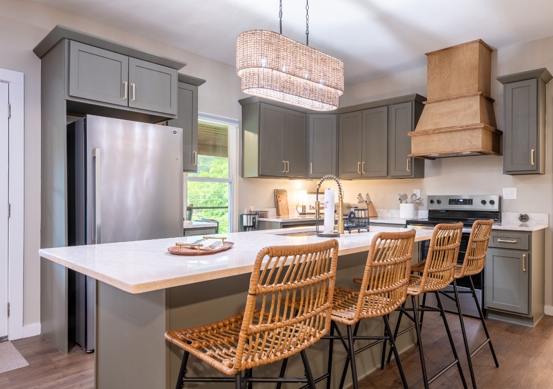 Step into your fully equipped kitchen, where sleek gray cabinetry meets warm wood accents and a spacious island invites you to gather with friends over coffee or cocktails.