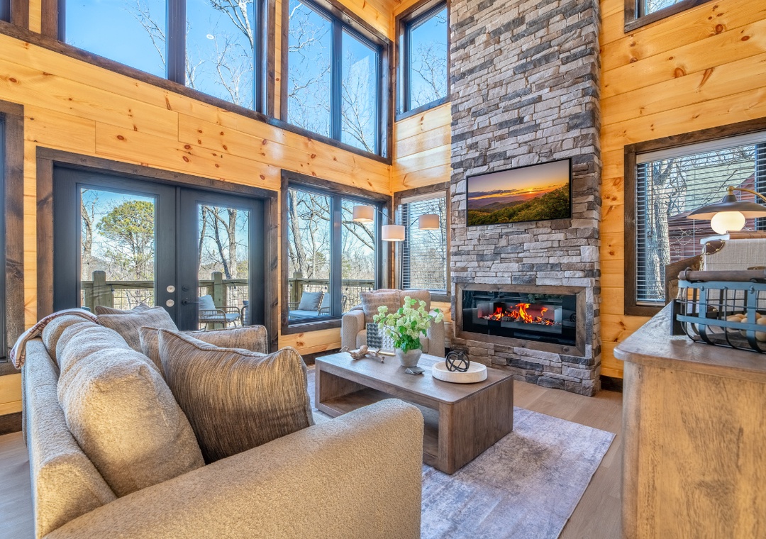 Cozy up in this stunning living room with soaring windows, crackling fireplace, and warm wood details perfect for your mountain getaway.