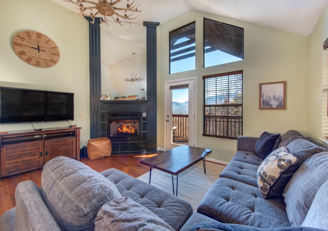 Cozy up in your spacious living room with soaring ceilings, crackling fireplace, and mountain views through expansive windows.