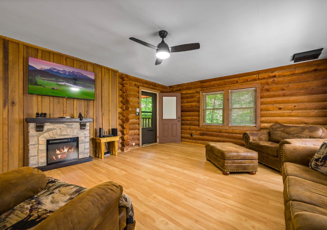 Cozy up in your rustic living room where warm wood walls and a crackling fireplace create the perfect mountain retreat atmosphere.