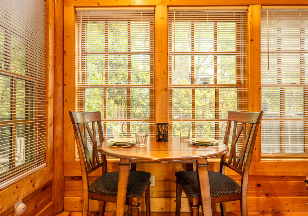 Gather around the warm wooden table and soak in peaceful forest views through sunlit windows—your tranquil spot for morning coffee or evening meals together.