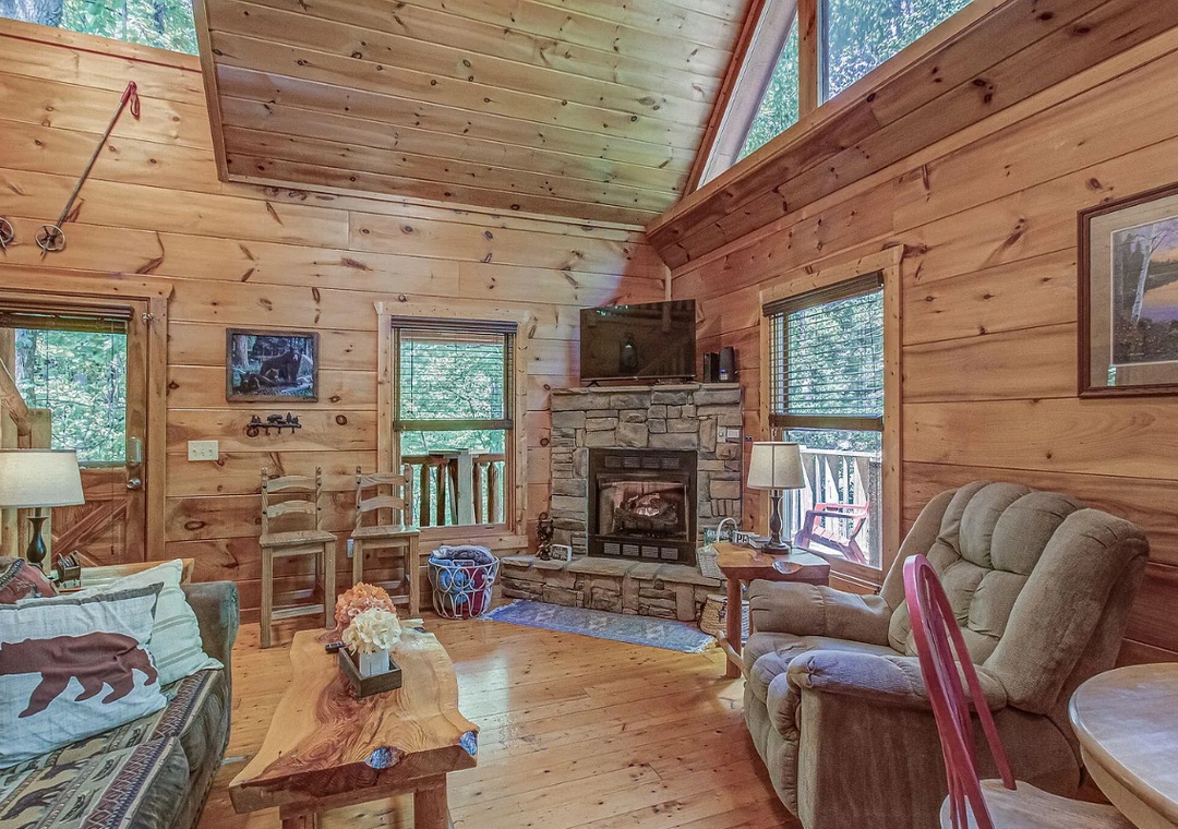 Cozy up in your rustic retreat with soaring ceilings, stone fireplace, and forest views streaming through tall windows.