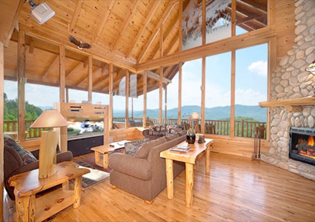 Relax in this stunning open living space with soaring wood beams, a cozy stone fireplace, and floor-to-ceiling windows framing breathtaking views.