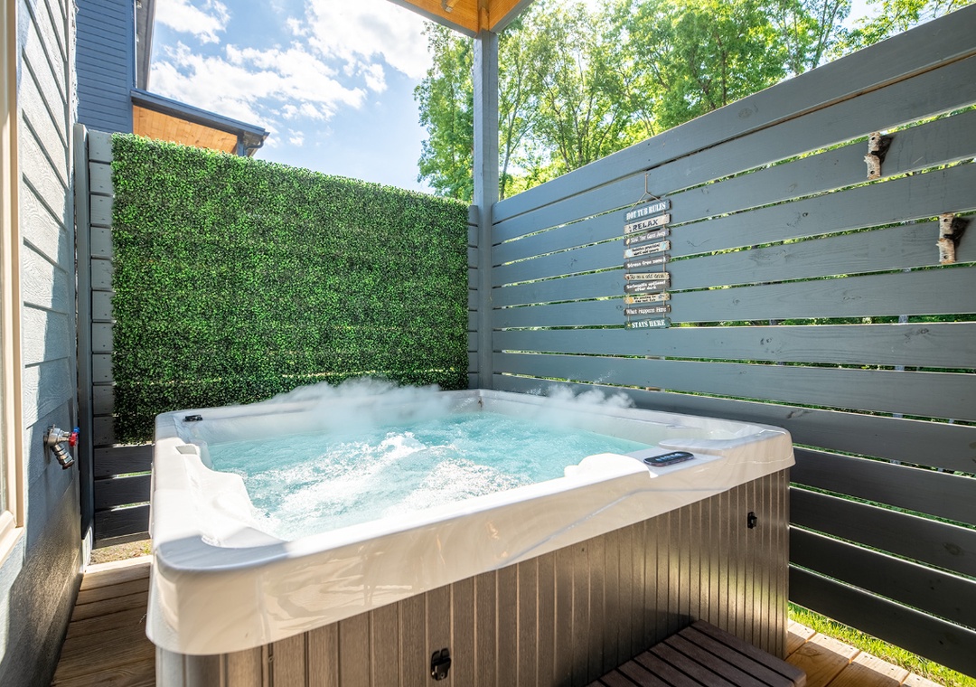 Slip into your private hot tub surrounded by lush greenery and privacy screens—picture yourself unwinding under the open sky with bubbles gently massaging away the day's stress.