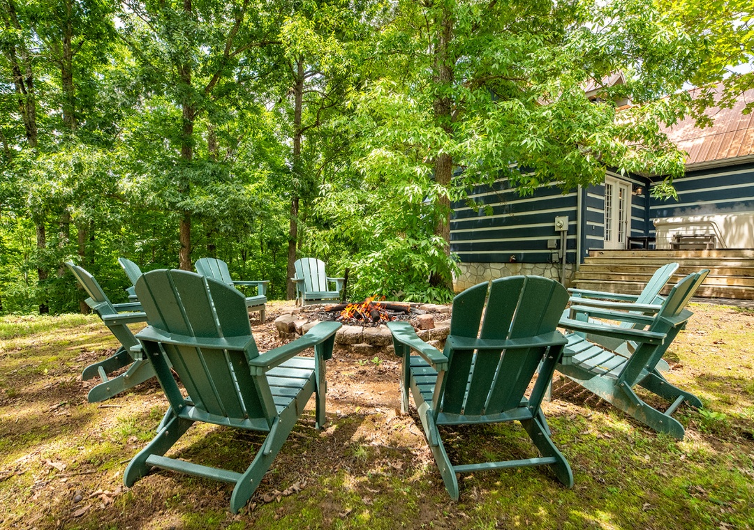 A secluded outdoor fire pit surrounded by Adirondack chairs, nestled among lush trees and natural greenery—perfect for peaceful evenings under the forest canopy.