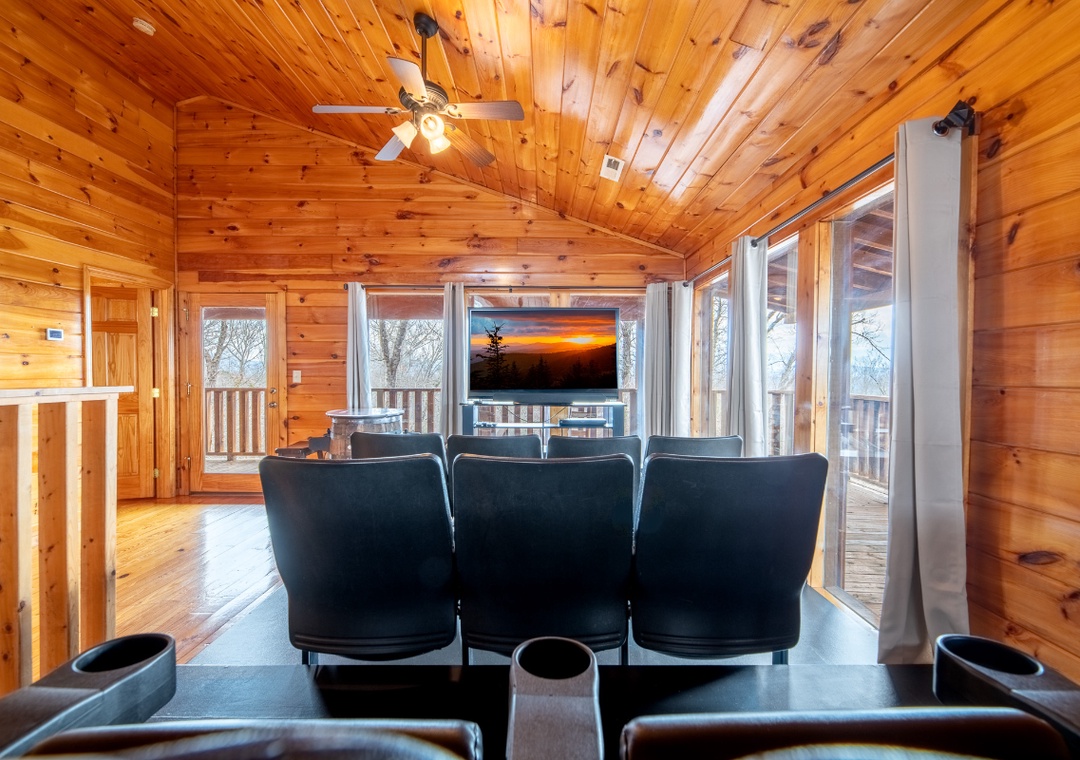 Relax in your cozy cabin theater room with warm wood walls, comfy leather seating, and stunning sunset views from the deck.