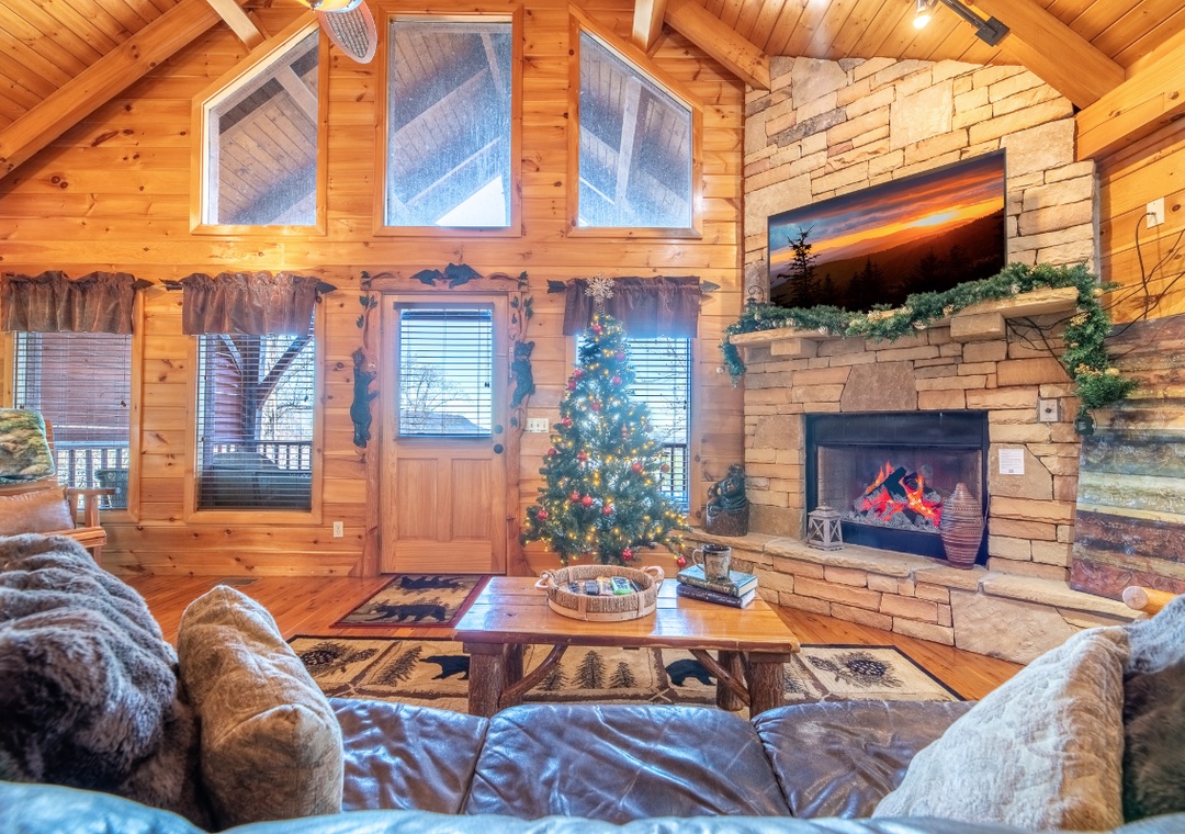 Cozy up by your crackling stone fireplace in this warm cabin living room, complete with festive Christmas tree and plush sofas.