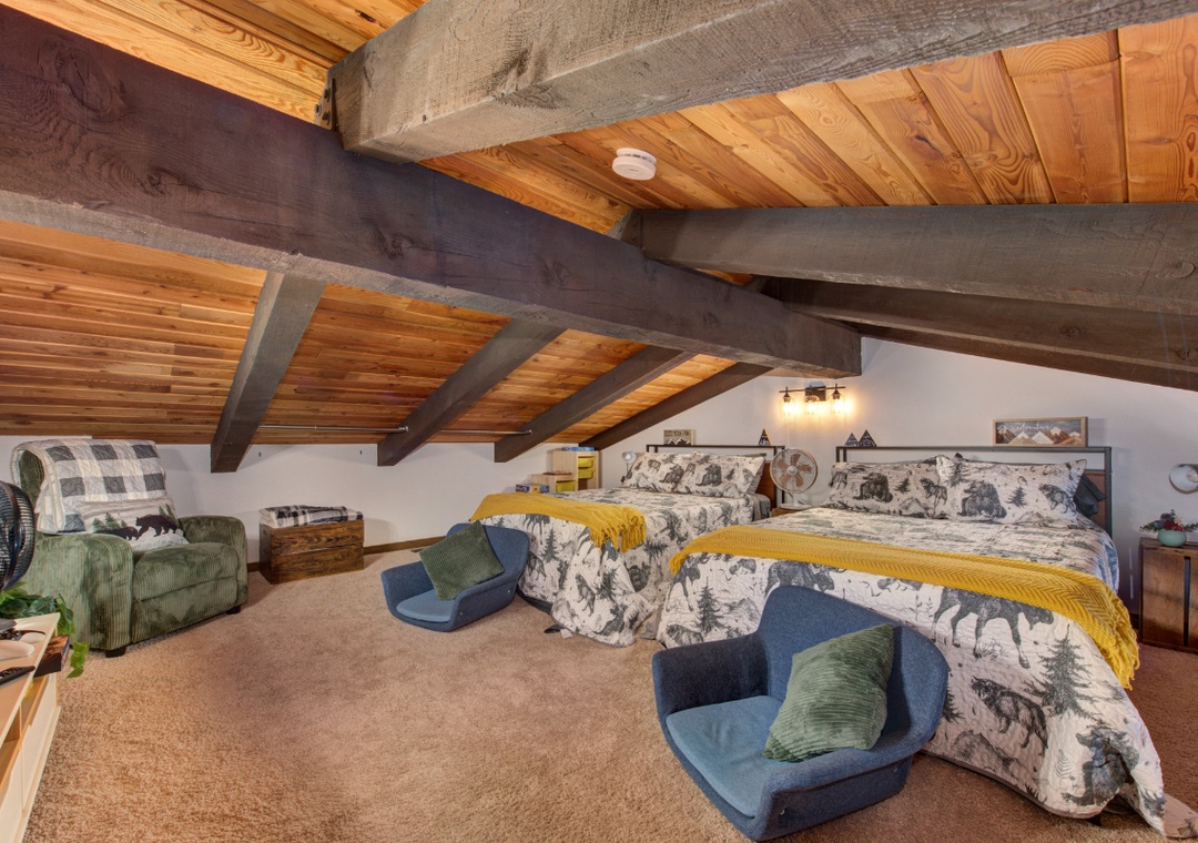 Cozy loft bedroom with rustic exposed beams where you'll sleep peacefully in comfortable beds with charming mountain-themed bedding and plush seating.