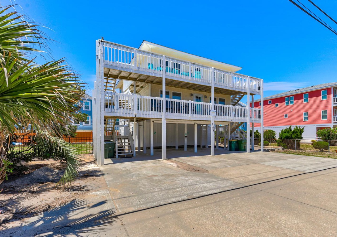 This beachside property features a multi-level design with covered parking, private balconies, and coastal landscaping, located in a vibrant neighborhood close to the shore.