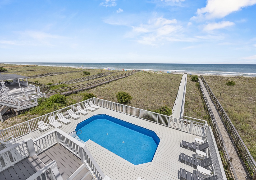 Oceanfront property featuring a private pool with direct beach access via wooden boardwalk pathways through natural dunes.