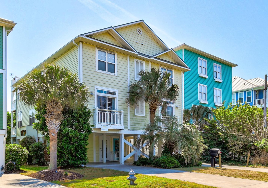 Charming coastal homes with vibrant colors and tropical palms create a welcoming beachside neighborhood atmosphere.