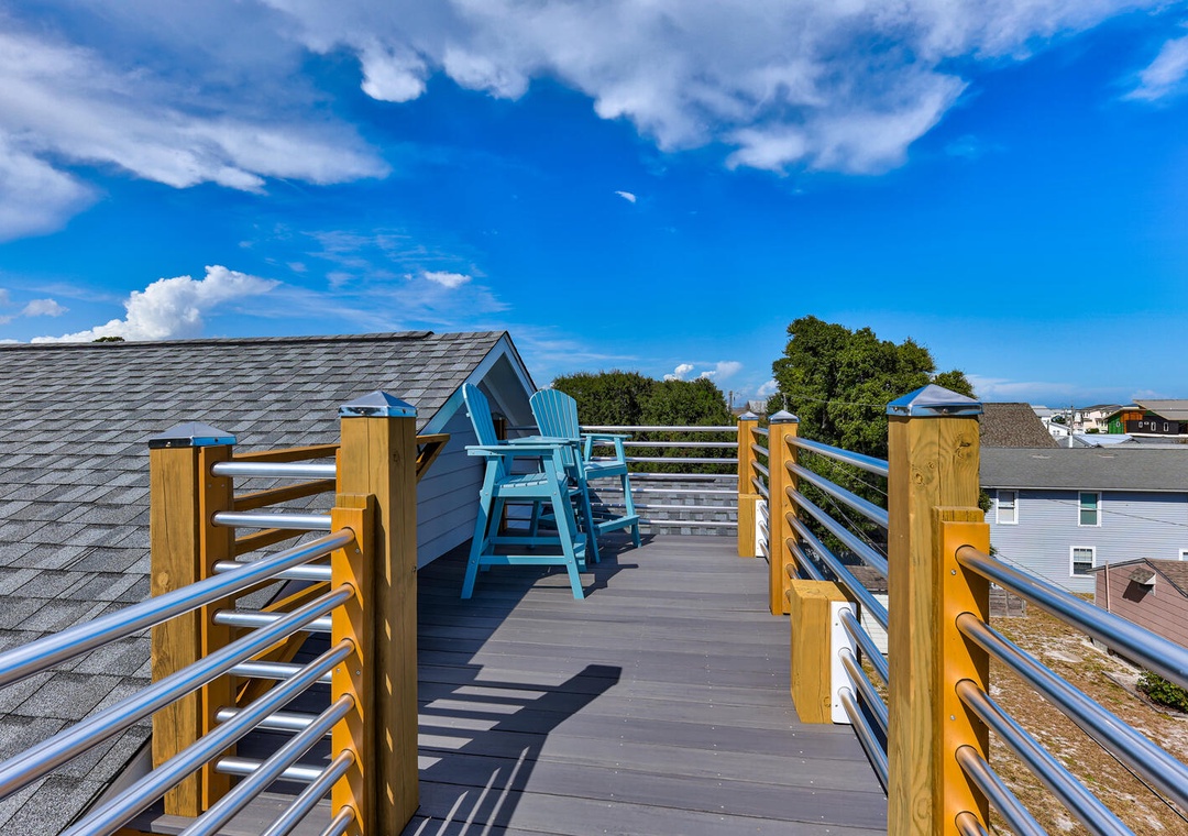 Step onto your private rooftop terrace where bright blue chairs await beneath endless skies, perfect for morning coffee or sunset cocktails.