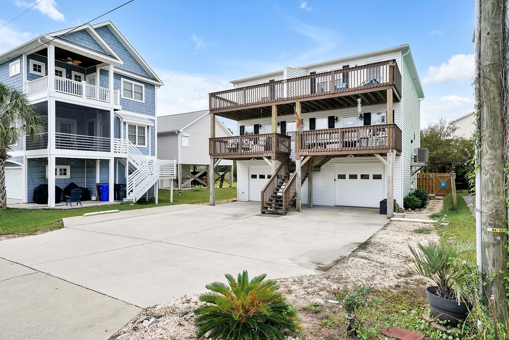 Coastal vacation rental property featuring multi-level design with private balconies, ground-floor parking, and tropical landscaping in a quiet residential neighborhood.